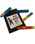 A set of colorful affirmation crayons arranged around a black book titled 'DEAR BLACK BOY, you are...' on a white background.