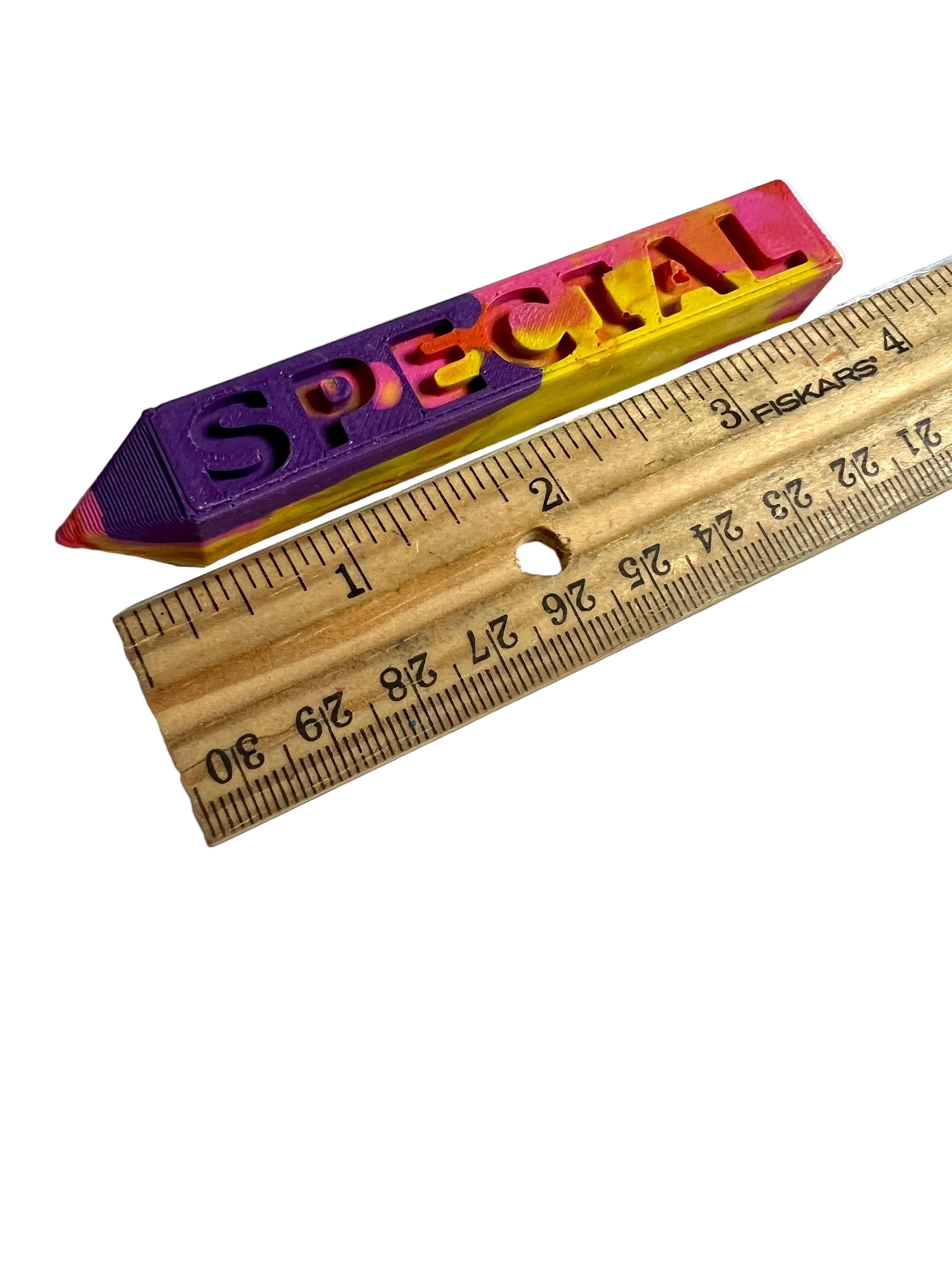 Multicolored crayon spelling 'SPECIAL' next to a wooden ruler on a white background
